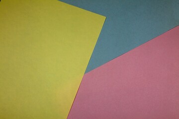 Top view of yellow, blue, and pink colored papers on the table