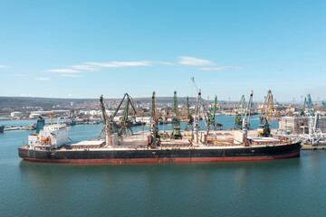 Black Sea Grain Initiative 2023 grain Deal. Port cranes loading of grain on a bulk carrier at sunny day. Panoramic shot made by drone