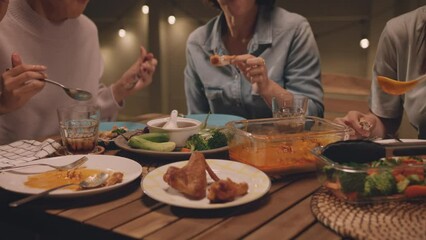 Enjoy eat yummy thai food with rice curry and drink at dine table outdoor house night party with mum. Asia older people mom and young adult child smile relax meet happy picnic meal warm time talk fun.