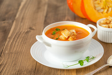 Pumpkin soup with croutons on wooden background. Copy space