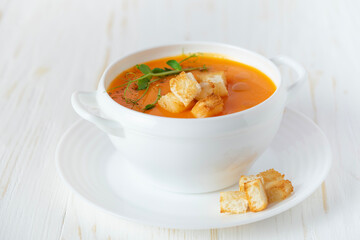 Pumpkin soup with croutons on white wooden background. Close up