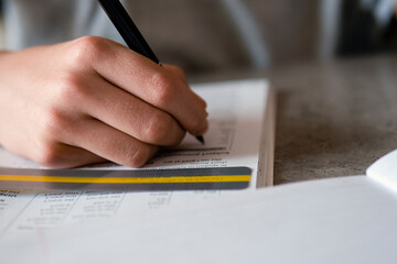 Kid affected by dyslexia doing homework, writing, reading notebook task using colorful overlay strip. Education, learning disability, reading difficulties concept