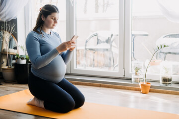 Pregnancy Workout Apps. Prenatal and Postnatal Workout. Stretching Yoga Exercise During Pregnancy Apps. Pregnant woman looking for Workout in phone.
