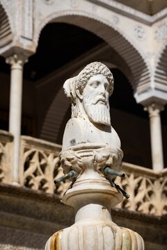 Vertical shot of statue of a man and Casa de Pilatos renascentist mansion in downtown Seville, Spain