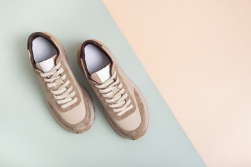 Beige women's leather sneakers top view on a green-beige background. Spring or autumn casual shoes
