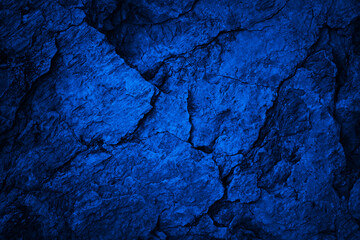 Toned cracked rock texture. Black dark blue stone texture background. Grunge. Navy blue rough surface. Close-up. Broken, damaged, collapsed.	
