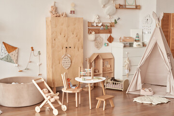 Children's educational wooden toys. Nursery decor. Scandinavian style playroom. Wooden stroller, table and chair © Aleksandr