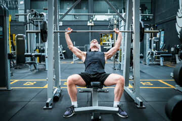 Male athlete exercising in the gym, lifting weights, pulling joints.