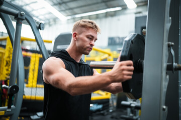 Male athlete exercising in the gym, lifting weights, pulling joints.