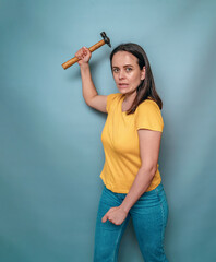 Woman holds in her hands and swings a hammer at the viewer. Female anger