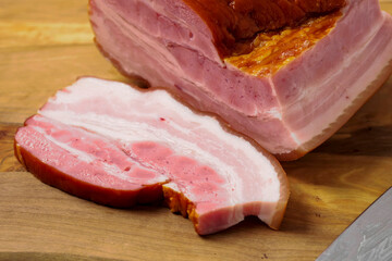 Traditional smoked Polish ham on a wooden cutting board. Popular East European food for any occasion. Pork product of high premium quality.