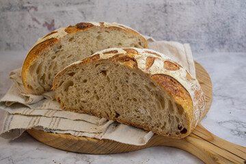 Sourdough bread, beautifully scored, on wooden board,, sliced to show interior