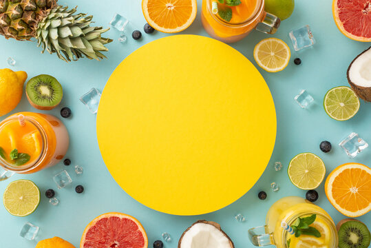 Indulge in some refreshing summer sips with this stunning top view flat lay photo of colorful citrus juices in glass jars, pineapple coconut on a blue background with blank circle for advertising