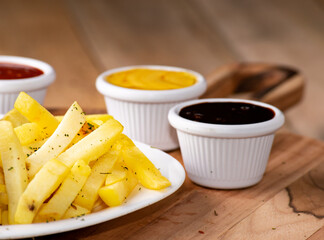 bbq chicken wings with french fries and ketchup, mustard and bbq on a rustic wooden table on a black background