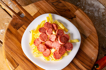 French fries with sausage on rustic wooden table on black background