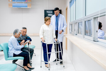 Caucasian doctor help to take care and support senior patient woman with walker to walk in front of pharmacy counter in hospital.