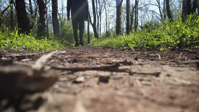 A camera captures a perspective from a very low vantage point on a hiking trail located in Veteran's Park, Lexington, Kentucky. The footage shows a person's feet walking past the camera.