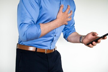 Man holding a phone in one hand while his other hand is on his chest indicating receiving bad news