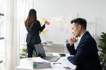 Professional businessman working with laptop computer with his coworker in the background.