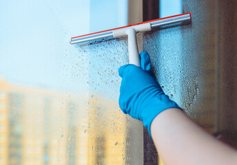 Window washing. Window cleaning with a squeegee and a wiper on a sunny day close-up. Dirty windows.