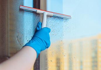 Window washing. Window cleaning with a squeegee and a wiper on a sunny day close-up. Dirty windows.