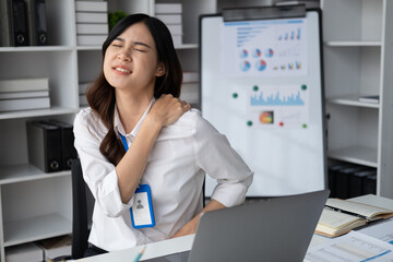 Asian businesswomen suffer from shoulder pain from working too much in an office.