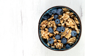 Bowl with blueberries and walnuts on white board