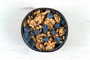 Bowl with blueberries and walnuts on white board