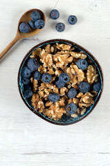 Bowl with blueberries and walnuts on white board