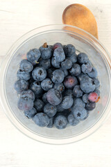 Plastic bowl with blueberries and wooden spoon