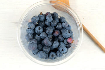 Plastic bowl with blueberries and wooden spoon