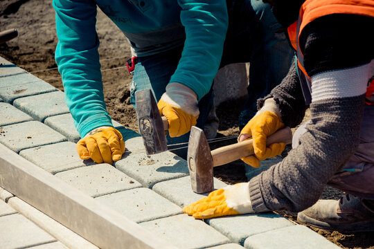 Close-up of two builders laying granite paving stones