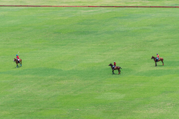 Three polo players on their horses play in a field on the outskirts of Lima, Peru