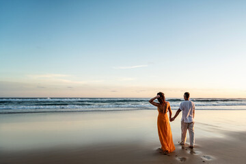 Romantic couple walking on sunset beach, enjoying evening light, relaxing on tropical summer vacation. Honeymoon. Love.
