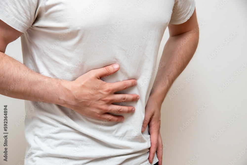 Wall mural Man, isolated on a blue background, holding his belly with one hand in pain