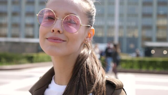 Funny smiling woman in casual clothes and sunglasses posing on the street background. Trendy positive girl in the city in sunny day going crazy