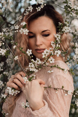 A beautiful woman in a dress near a cherry blossom. Spring Day