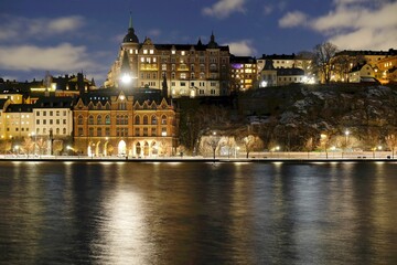 Fototapeta na wymiar Beautiful scenery of illuminated Stockholm waterfront view towards Sodermalm district with historic Mariahissen building and Monteliusvagen, Sweden