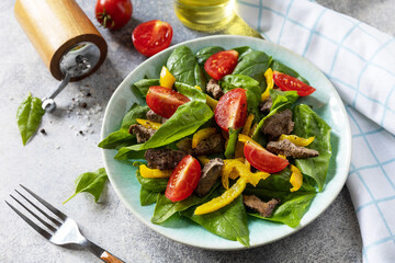 arm salad of young spinach, chicken liver, tomatoes and grilled peppers with spices and balsamic. Healthy keto diet low carb. 