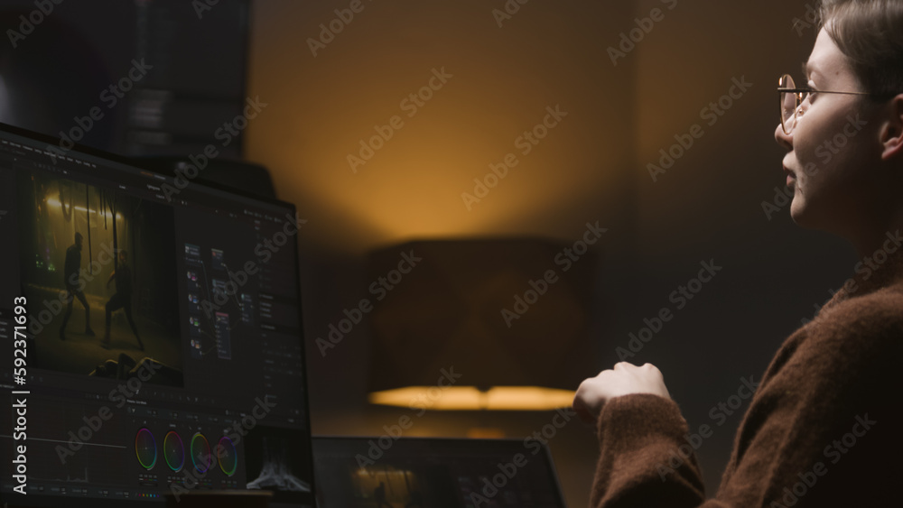 Poster female video maker works in studio on computer, uses color grading control panel. the colorist edits