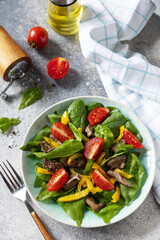 Warm salad of young spinach, chicken liver, tomatoes and grilled peppers with spices and balsamic. Healthy keto diet low carb.