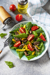 Warm salad of young spinach, chicken liver, tomatoes and grilled peppers with spices and balsamic. Healthy keto diet low carb. Copy space.