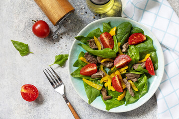 Warm salad of young spinach, chicken liver, tomatoes and grilled peppers with spices and balsamic. Healthy keto diet low carb. View from above.