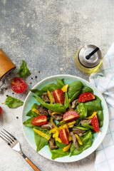 Warm salad of young spinach, chicken liver, tomatoes and grilled peppers with spices and balsamic. Healthy keto diet low carb. View from above. Copy space.