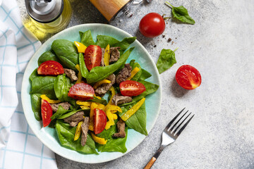 Warm salad of young spinach, chicken liver, tomatoes and grilled peppers with spices and balsamic. Healthy keto diet low carb. View from above. Copy space.