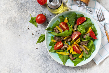 Warm salad of young spinach, chicken liver, tomatoes and grilled peppers with spices and balsamic. Healthy keto diet low carb. View from above. Copy space.