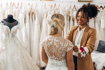 Happy tailor is doing some final alterations with the wedding dress on the bride