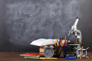 Back to school - books and microscope on the desk, Education concept. Blackboard background