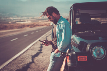 One man travel with car and standing outside the vehicle using online mobile phone app maps to...