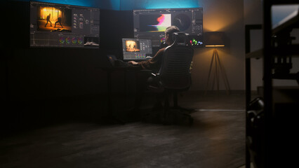 Female editor works in studio on computer using color grading control panel and professional video...